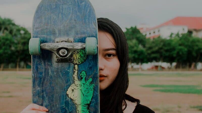 trucks de skateboard sur une planche tenue par une fille