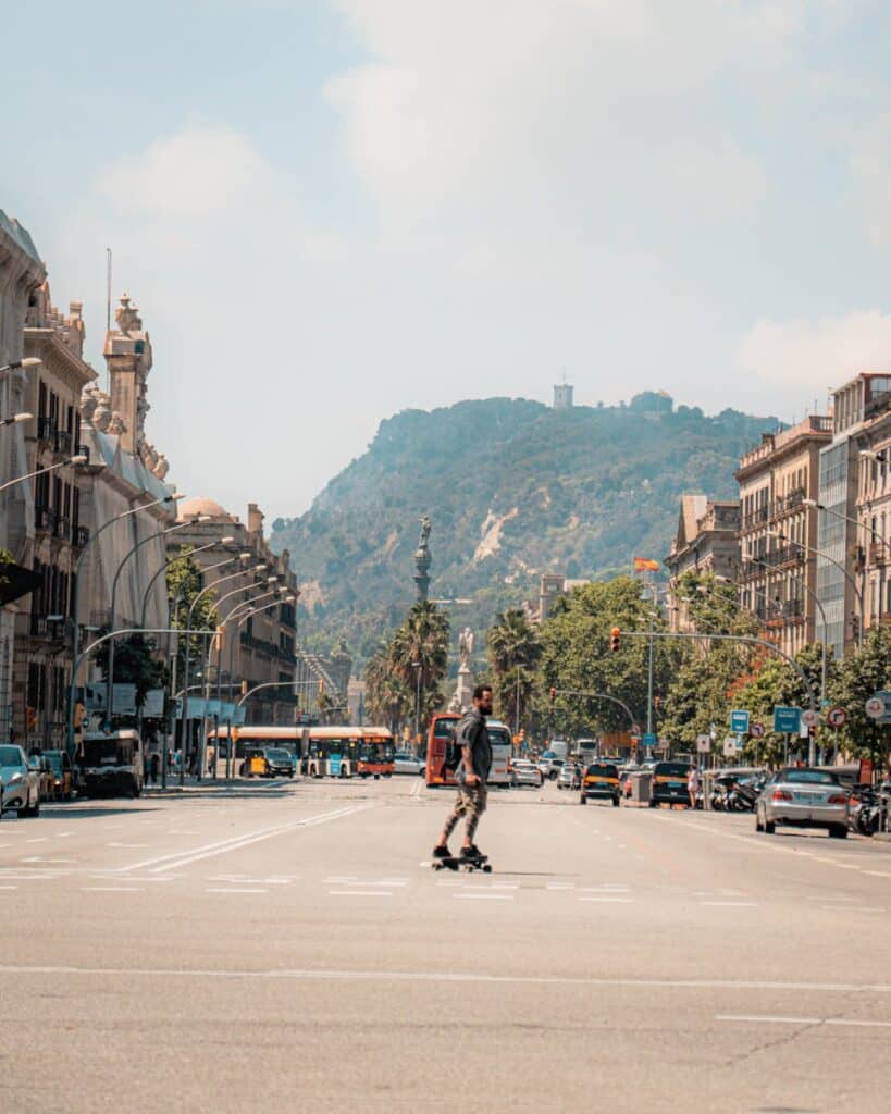 Urban skateboarder crossing street in Barcelona with iconic backdrop.